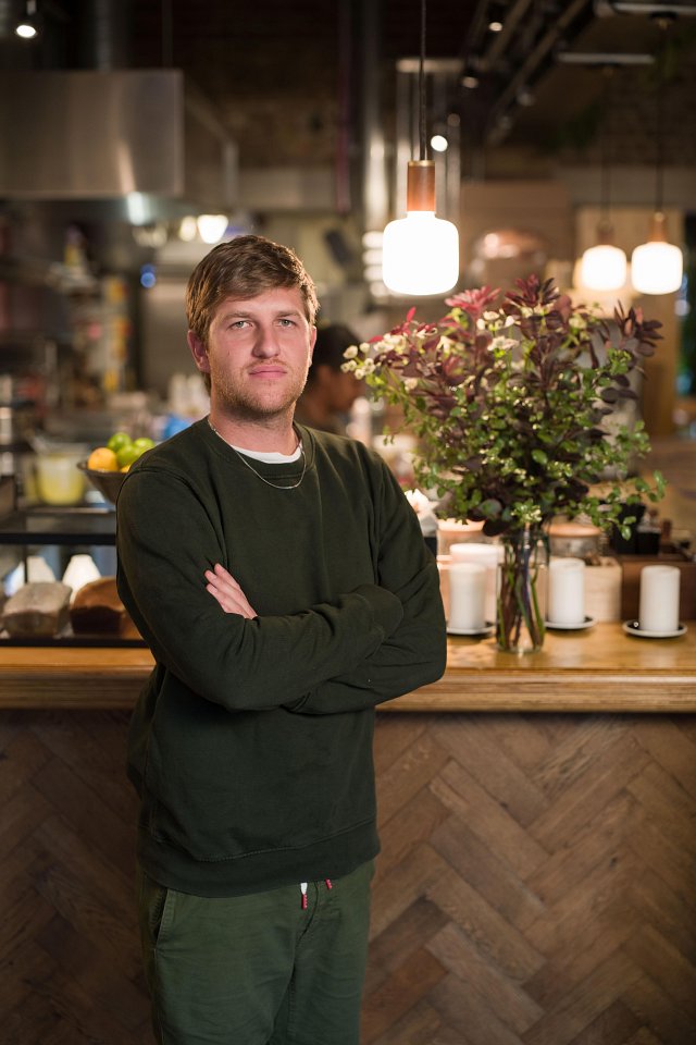 Man with arms crossed in front of wooden restaurant counter