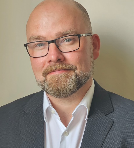 Close up headshot of a bald man wearing glasses