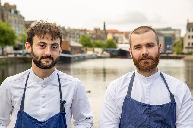 Two chefs in aprons standing by a river