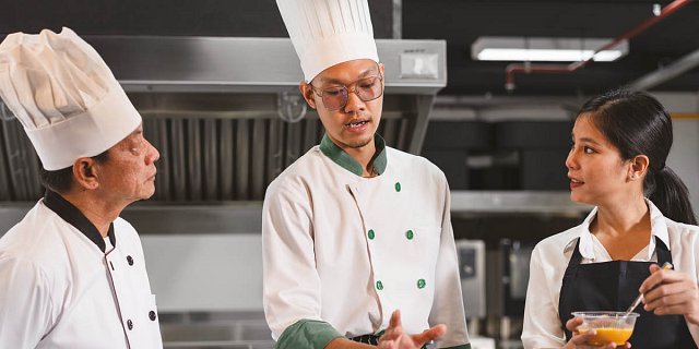 Man in chef whites briefs kitchen team